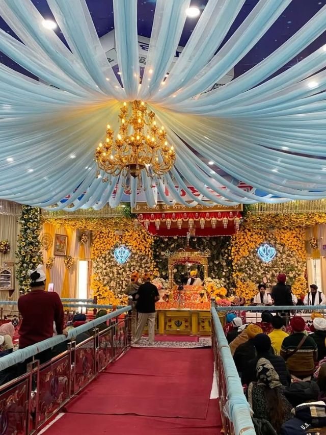 Valley of Flowers, Uttarakhand: How to Reach, Trek, Best Time, Complete Travel Guide 14 Interior of a beautifully decorated Gurdwara with a large golden chandelier, light blue ceiling drapes, and a flower-adorned altar.