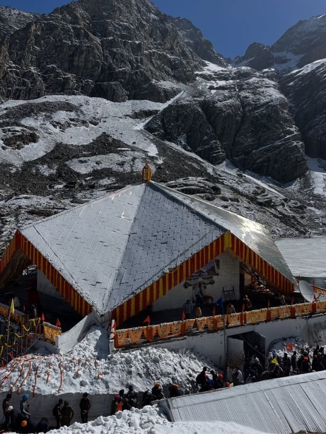 Valley of Flowers, Uttarakhand: How to Reach, Trek, Best Time, Complete Travel Guide 13 A stone temple with a distinct pyramid-shaped roof surrounded by thick snow and steep rocky mountains under a clear blue sky.