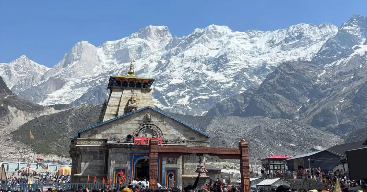 Char Dham Yatra Registration, Route Map, Itinerary, Packages & Helicopter Booking 8 The majestic grey stone temple stands proudly against a backdrop of massive, snow-covered Himalayan peaks under a clear blue sky.