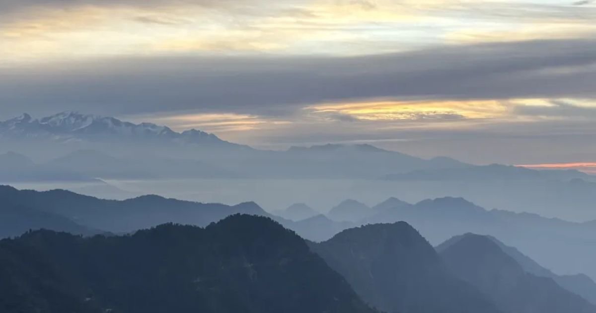 Kartik Swami Temple, Uttarakhand: How to Reach, Fare, History and Complete Travel Guide 6 Layered mountain ridges fading into a misty, pale yellow and blue sunset sky.