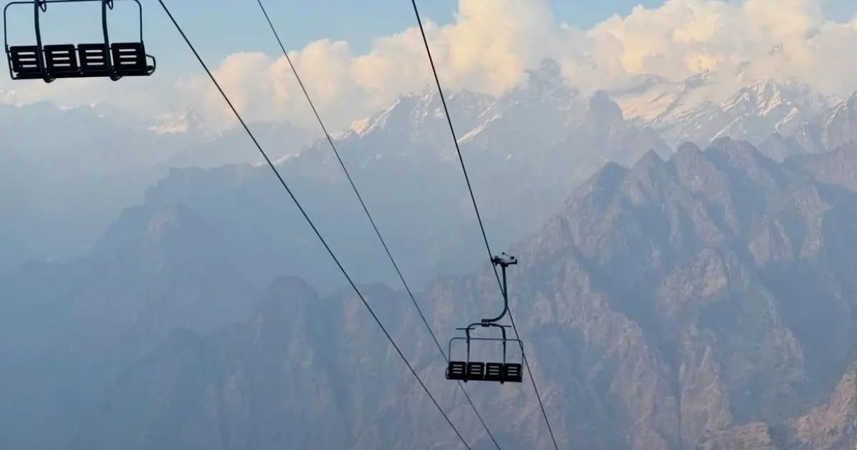 12 Best Places to Visit in Uttarakhand in October for Nature Lovers 10 Cable car chairlift gliding high above hazy mountain peaks on a clear day.