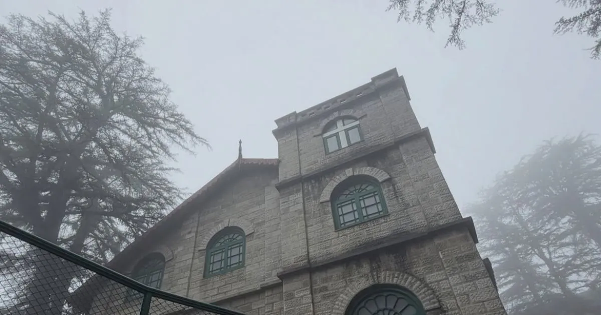 12 Best Places to Visit in Uttarakhand in October for Nature Lovers 2 A historic stone church building standing among tall cedar trees in heavy Mussoorie fog.