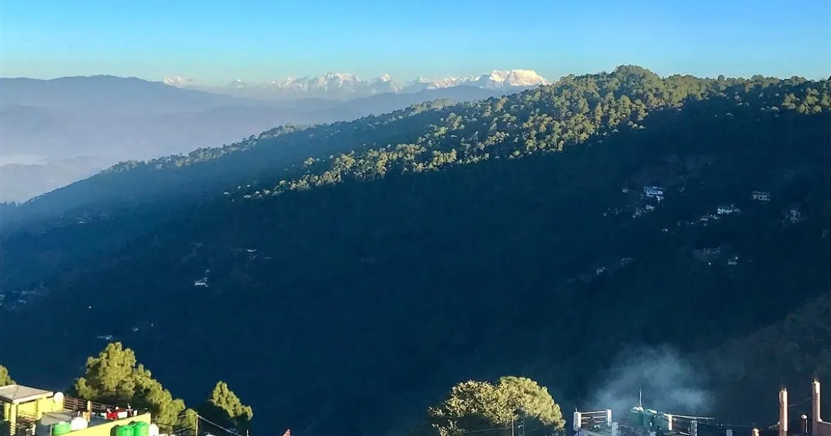 12 Best Places to Visit in Uttarakhand in October for Nature Lovers 3 Rolling green hills leading toward snow-peaked Himalayan mountains in Ranikhet.