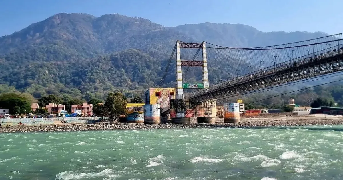 12 Best Places to Visit in Uttarakhand in October for Nature Lovers 11 A large suspension bridge spanning across the green river with hills in Rishikesh.