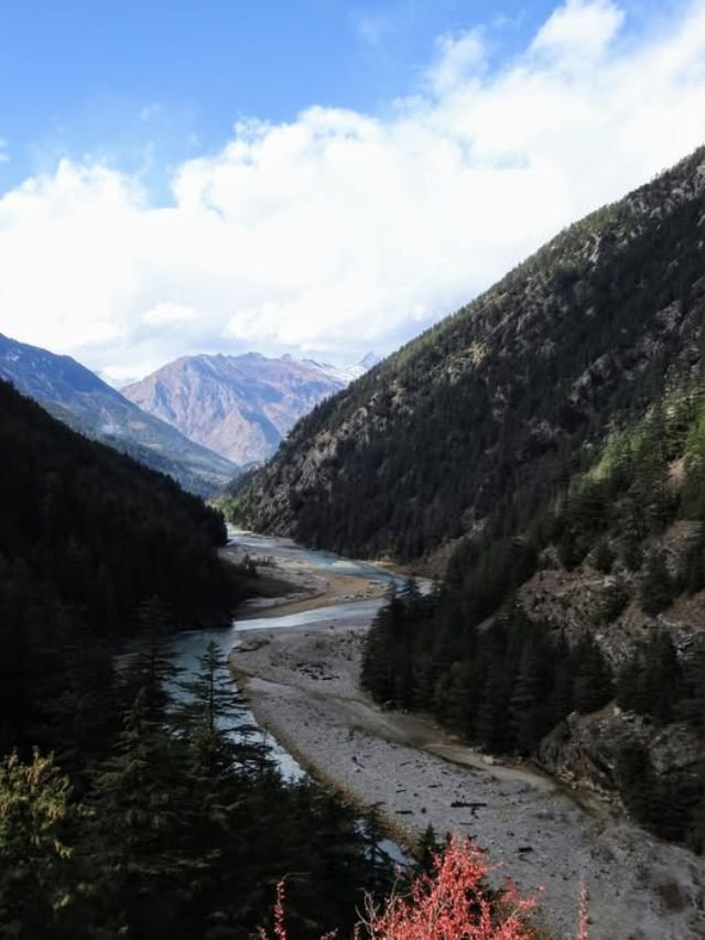 Visit Harsil Valley: How to Reach, Near Hotels, Best Time | Complete Travel Guide 18 A winding river flows through a deep mountain valley near Harshil.