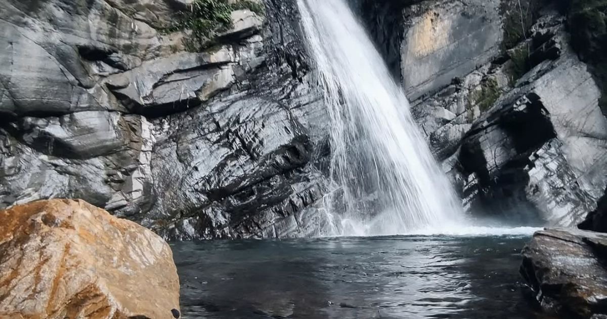 A tall waterfall dramatically falls into a rocky pool. A scenic and refreshing stop on Easy Treks Near Dehradun.