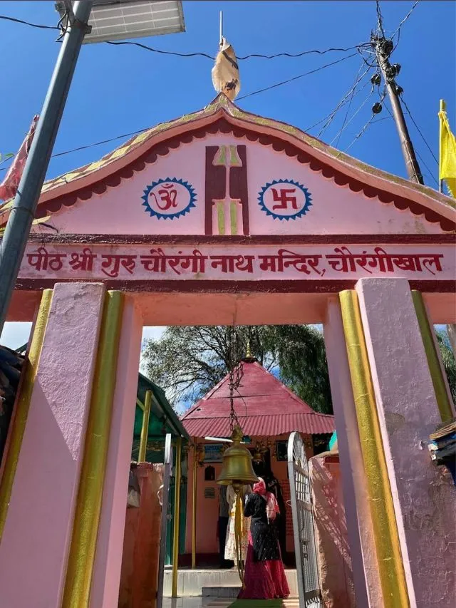 Nachiketa Tal Trek: A Complete Guide With Route Map and Tips 3 The pink entrance gate of the temple at Chaurangikhal with a central hanging bell.